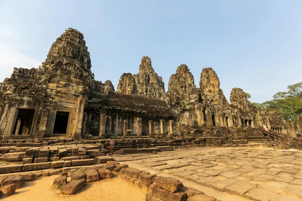 Stunning view of Angkor Wat temple ruins against clear blue sky, showcasing ancient architecture.