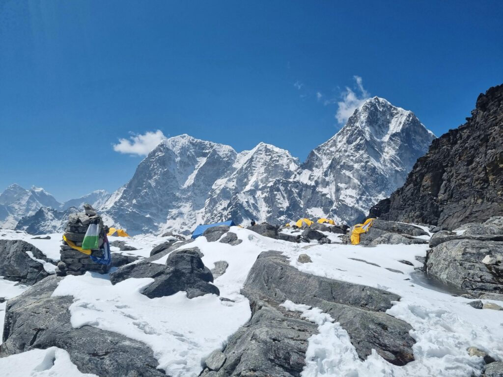 Snow-covered Himalayan peaks and colorful prayer flags at a base camp in Khumjung, Nepal.