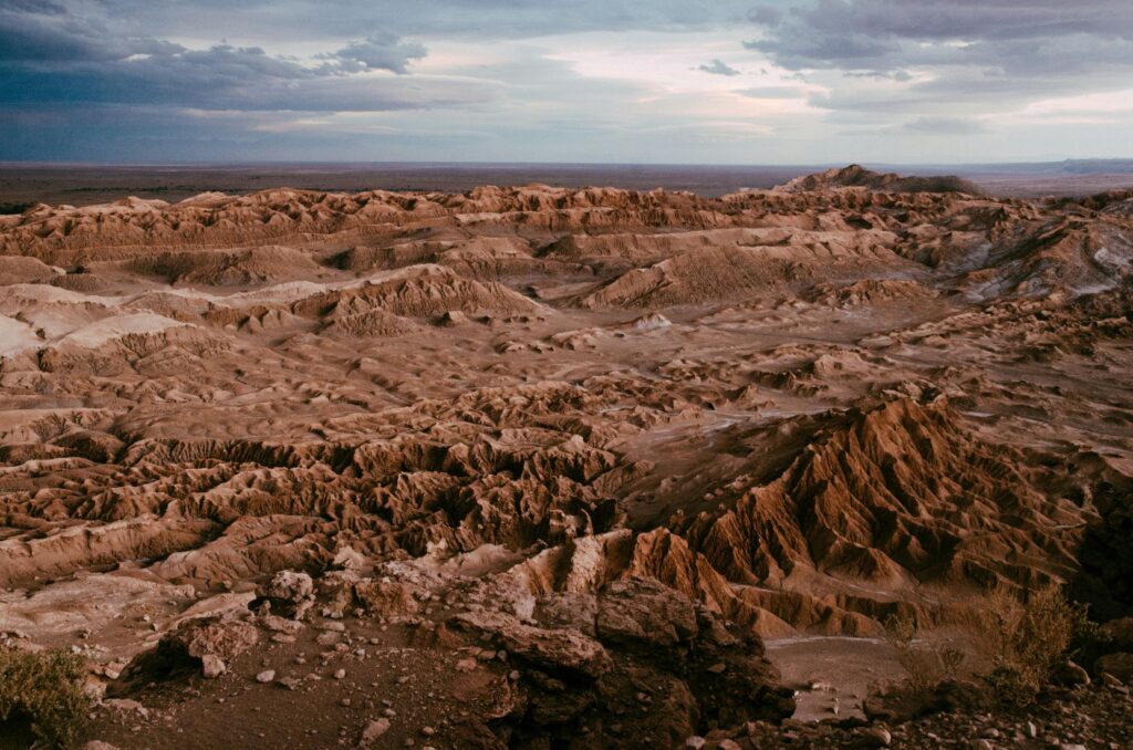 Stunning view of Valle de la Luna in the Atacama Desert with rugged terrain under a dramatic sky.
