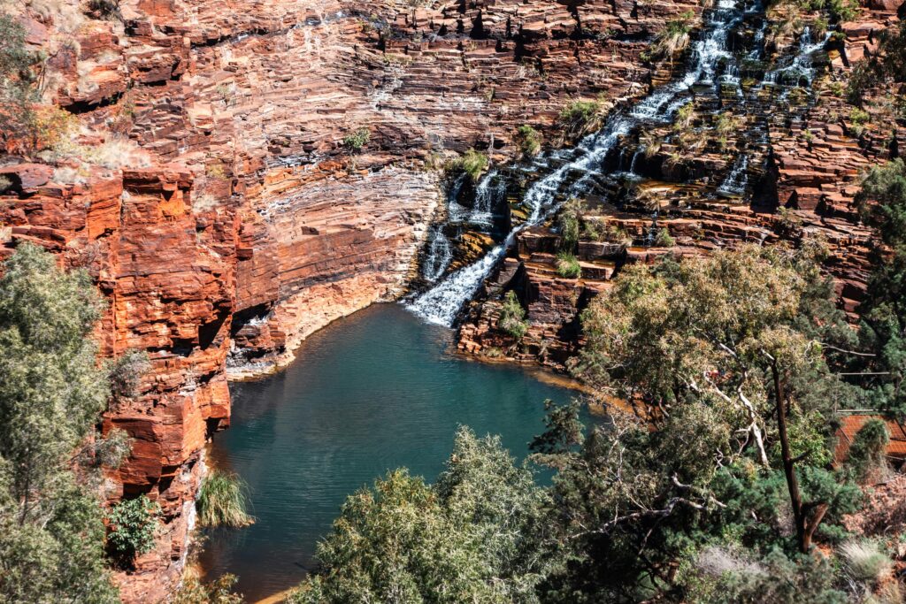 Beautiful waterfall cascading over red rock cliffs in Karijini National Park, Australia.