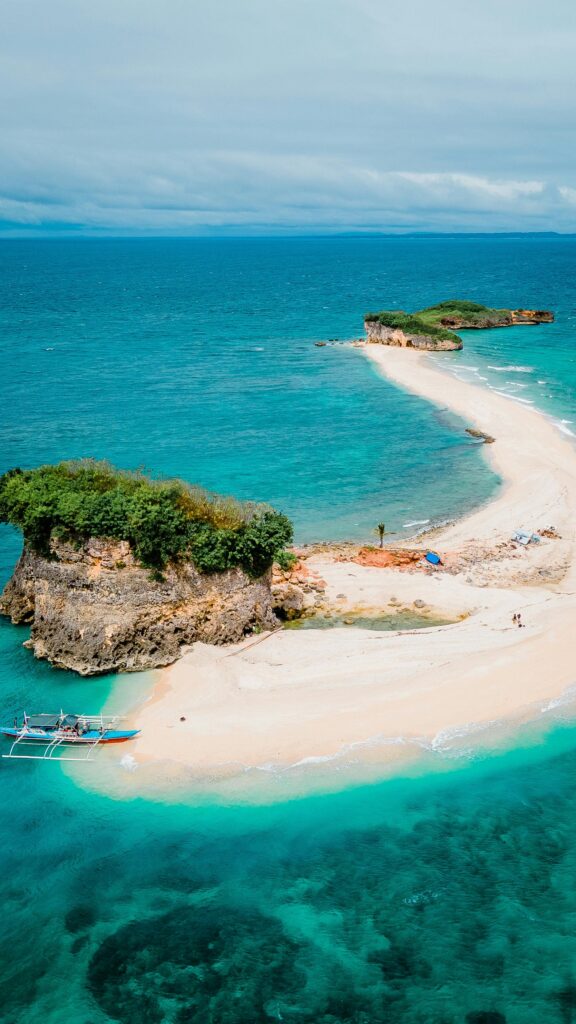 Explore a breathtaking aerial view of a pristine beach in the Philippines, showcasing vibrant blue waters and lush greenery.