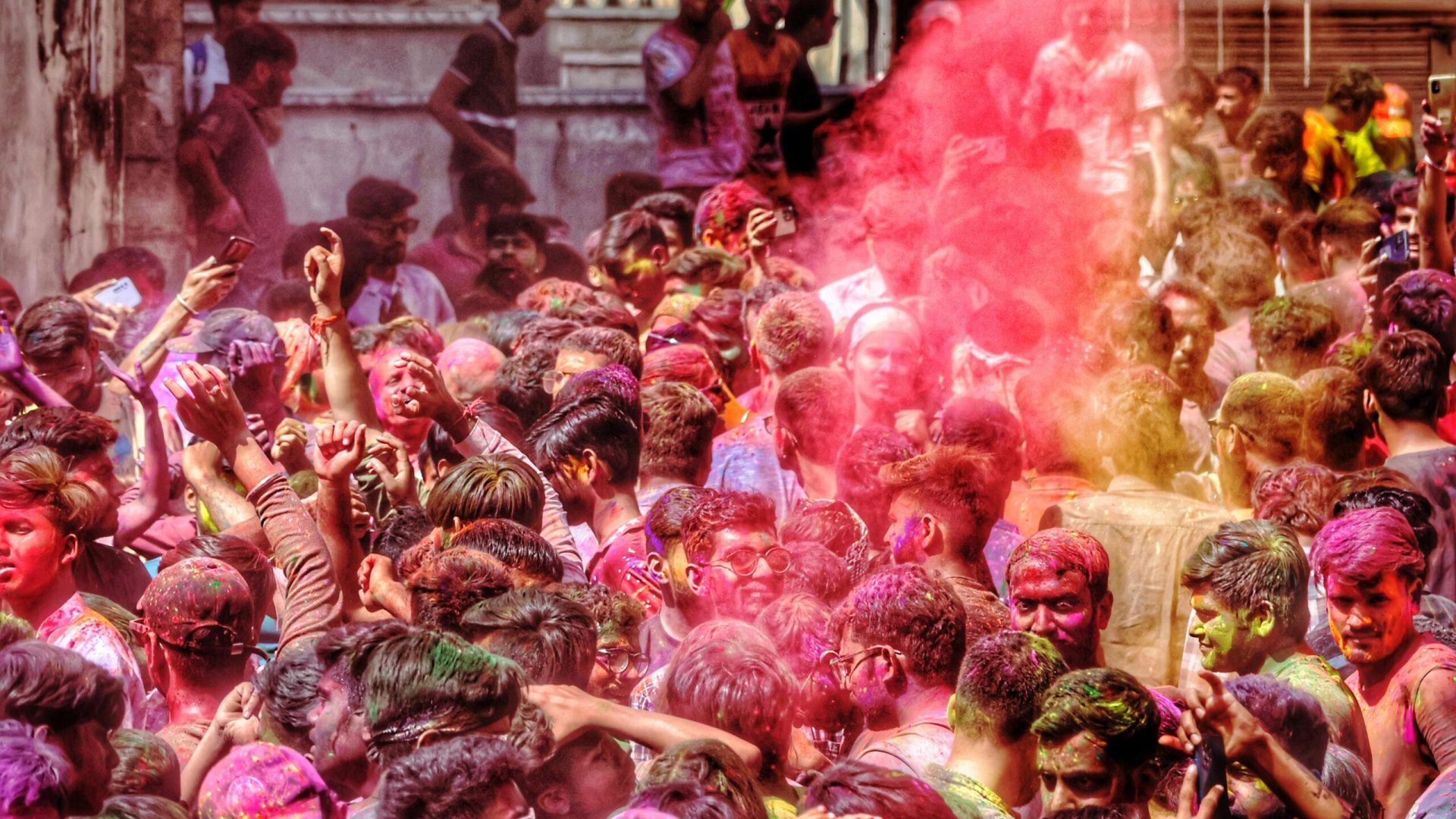 A lively crowd celebrates Holi with colorful powders in Udaipur, India.