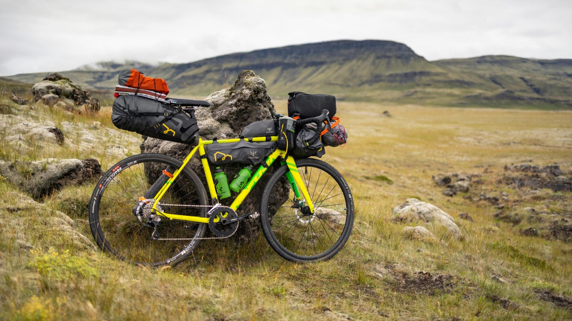 A fully loaded bike rests against rocks in Iceland's rugged highlands, perfect for expedition travel.