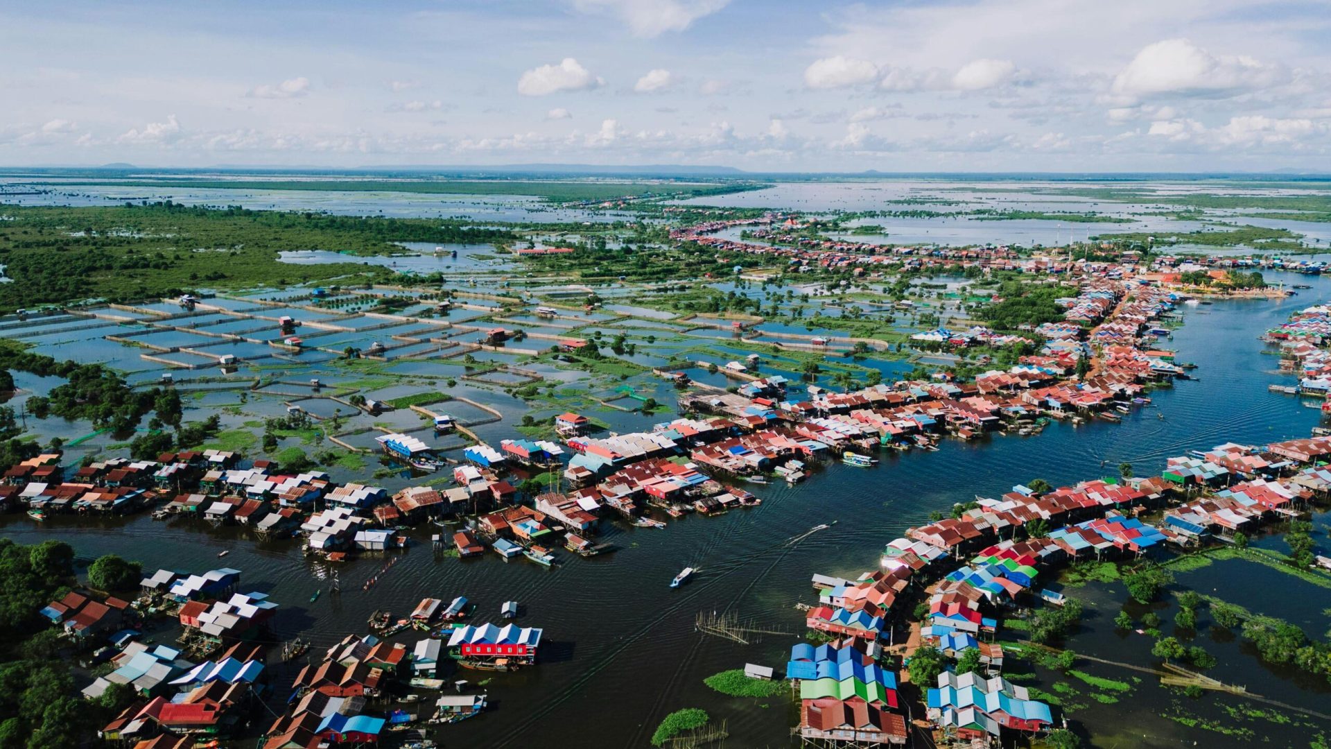 A stunning aerial view of the vibrant floating village in Kampong Khleang, surrounded by water and lush landscape.