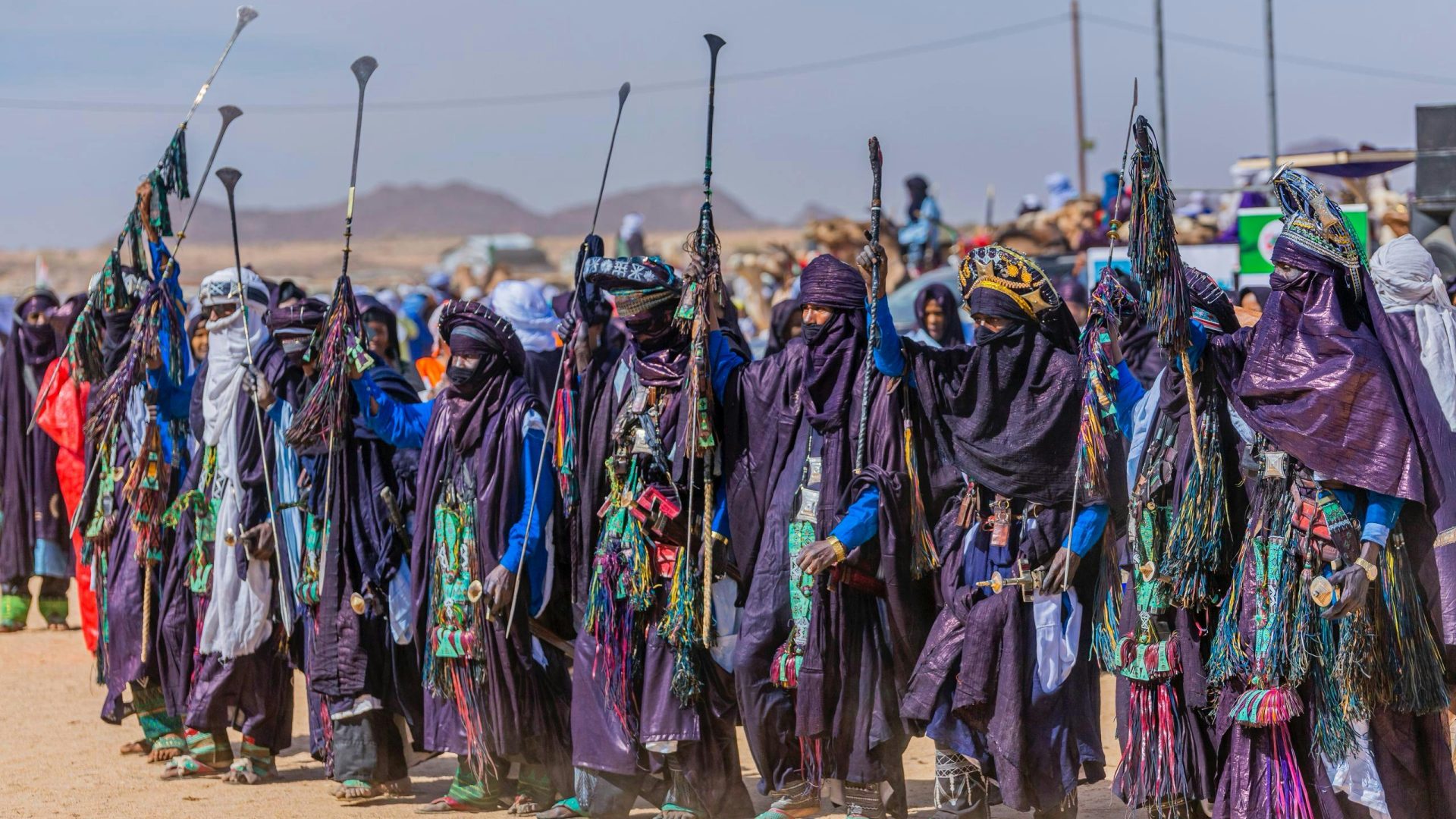 Tuareg people in vibrant traditional garb celebrating at a desert festival.