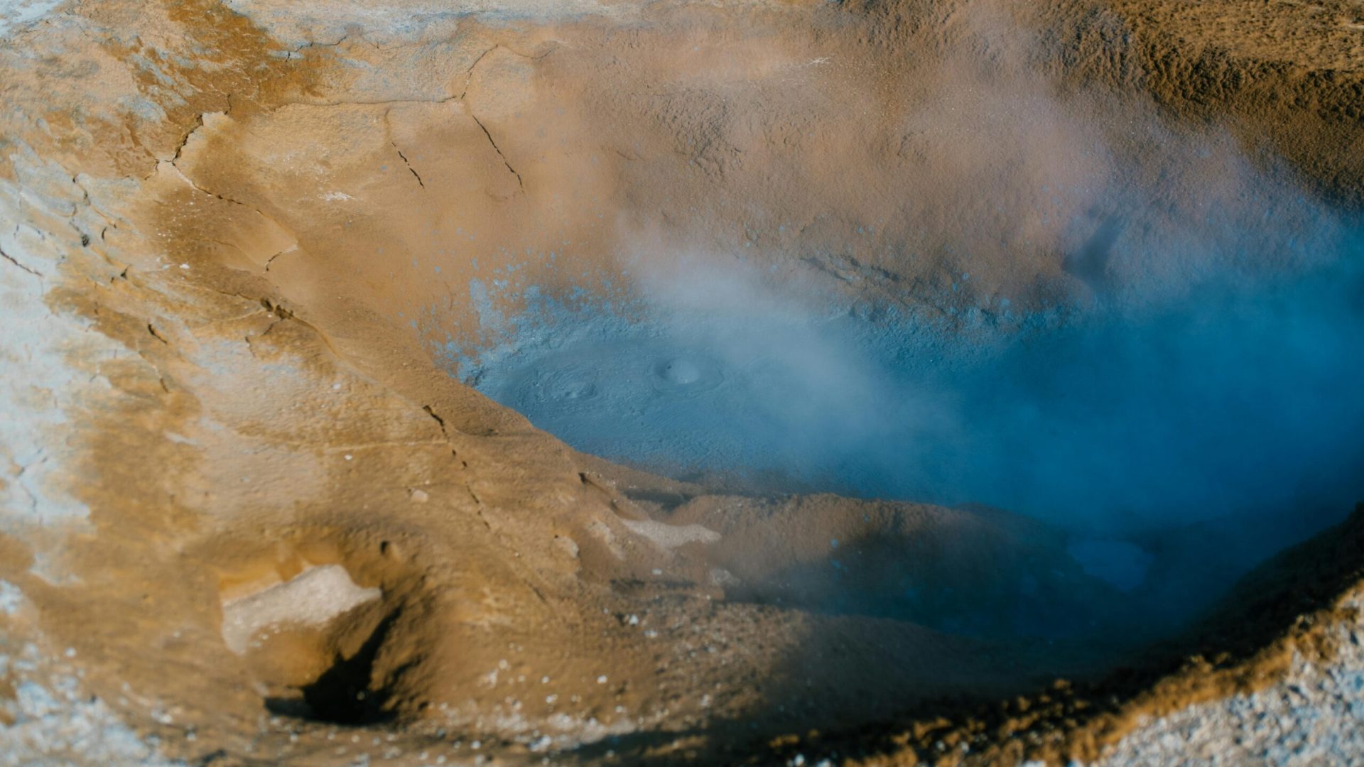 Elevated view of Iceland's unique geothermal landscape featuring steam and colorful mineral deposits.