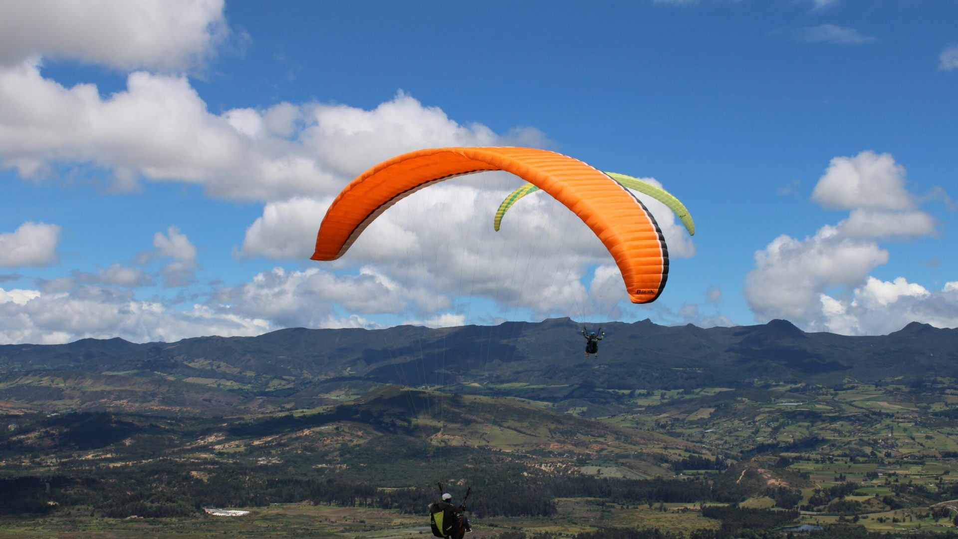 Experience the thrill of paragliding over a breathtaking mountain vista under a clear blue sky.